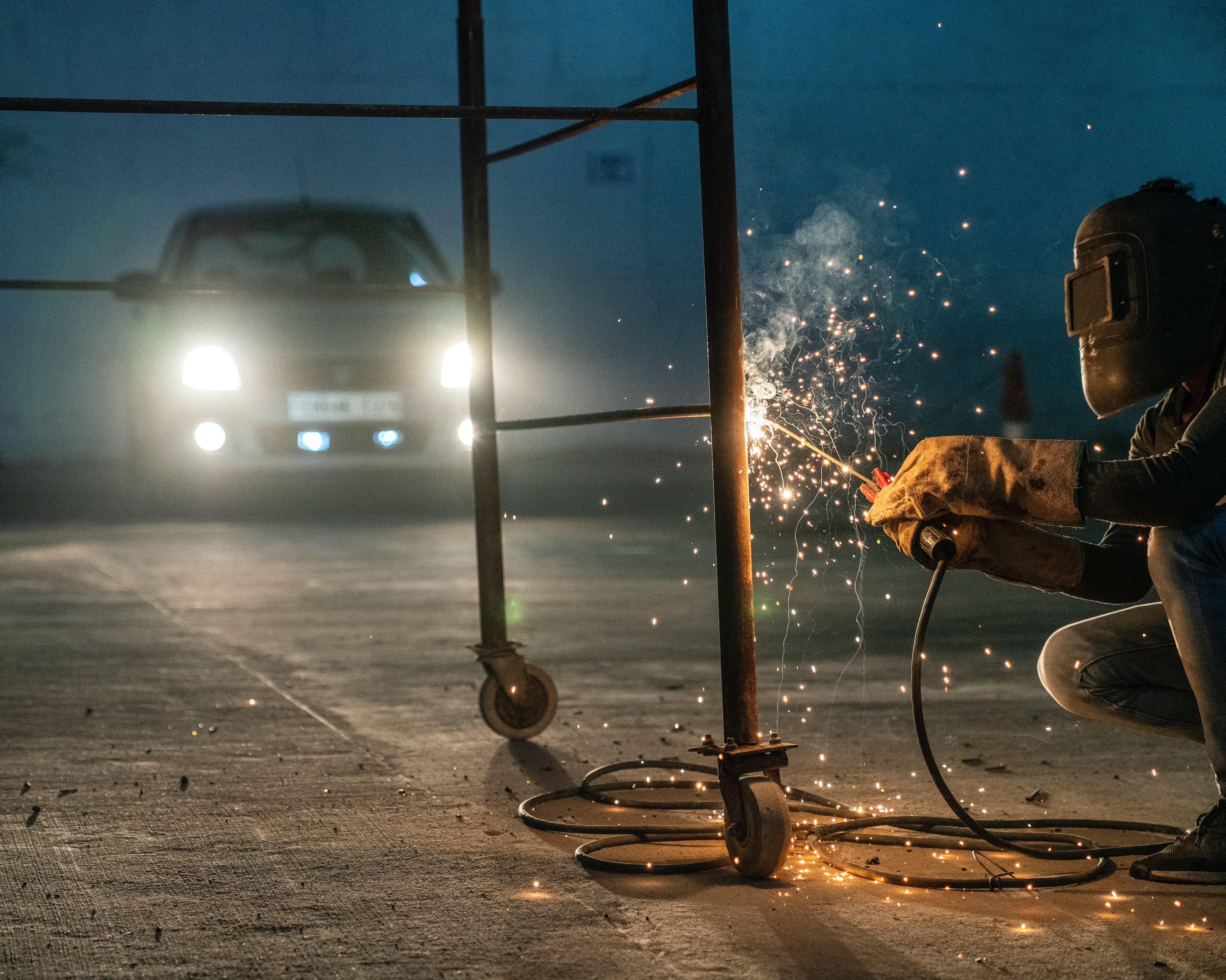 a man welds table in front of car